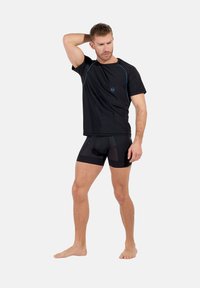 Svart atletisk T-shirt med blå accenter och shorts. T-shirten har rundad halsringning och korta ärmar; shortsen är åtsittande med texturerade paneler.