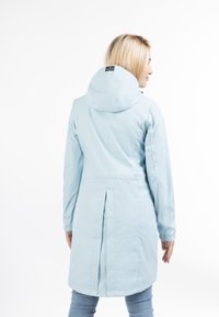 Impermeabil albastru deschis cu glugă, având un pliu pe spate, mâneci lungi și margine dreaptă. Textură netedă și design minimalist.