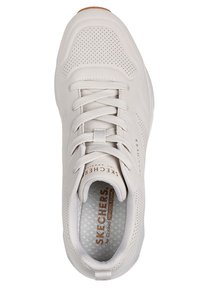 Helle graue Sneaker aus einem glatten Material, mit perforierten Akzenten und weißen Schnürsenkeln. Mit einem braunen Logo auf der Zunge und einer strukturierten Innensohle.