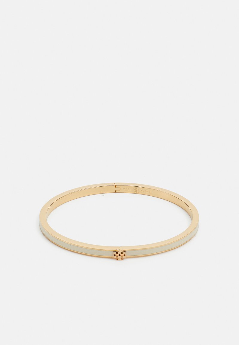 Zlatý kovový náramok s hladkým, lesklým povrchom. Má úzky dizajn a centrálny dekoratívny prvok s logom.