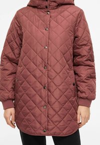 Quiltet lang jakke i burgunder, med hette, trykknapper, ribbestrikkede mansjetter og sidelommer. Jevn, blank tekstur med diamantmønster.