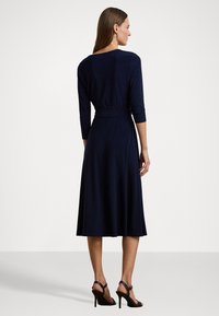 Abito blu navy con maniche a tre quarti, una cintura in vita e una gonna svasata, realizzato in tessuto morbido. Tacchi non inclusi.