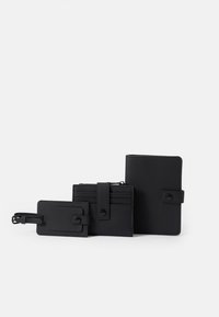 Conjunto de carteira em couro preto, incluindo um porta-passaporte, um porta-cartões com fecho de botão, e uma etiqueta de identificação, apresentando uma textura suave e um design minimalista.