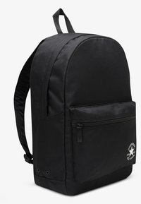 Must seljakott, millel on sile kangapind, ümar kuju, esiküljel lukuga tasku ja alumises paremas nurgas kummist Converse'i logo.