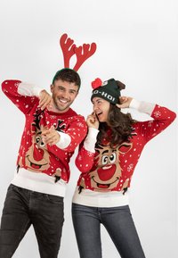 Red Christmas sweaters with reindeer designs and white snowflakes, worn with green and brown themed hats. Featuring ribbed cuffs and hems.