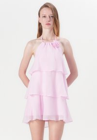 Roze halter haljina od laganog, slojevitog šifona. Sadrži cvjetni detalj na ramenu i fluidan, slojevit dizajn.