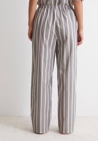 Graue und rosa gestreifte Wide-Leg-Hosen mit elastischem Bund. Glattes Material, gerader Schnitt und gebürstete Saumdetails.