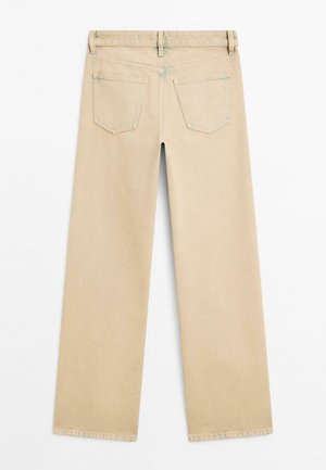 Jeans beige a vita alta con gamba larga e una texture liscia. Presentano due tasche posteriori e un orlo pulito. Cuciture a contrasto lungo la vita e le tasche.