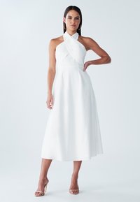Bílá šatová šaty s halter krkem a úzkým korzetem a volnou sukní. Vyrobené z lehkého materiálu, s elegantním, minimalistickým designem.