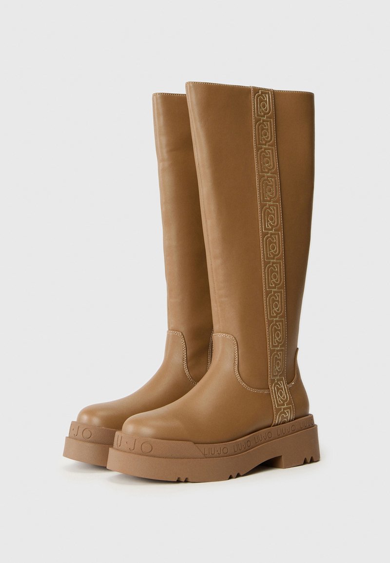 Braune knöchelhohe Lederstiefel mit dicken Gummisohlen und dekorativem gesticktem Seitenstreifen, geprägt mit dem Markennamen am Sohlenrand.