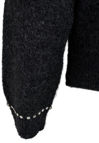 Črna pletena rokavica puloverja s teksturirano, puhasto površino. Vključuje vrsto svetlečih dodatkov na manšeti za dodatne podrobnosti.