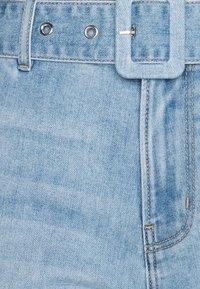 Vaaleansiniset farkut, joissa on kangashihna ja metalliset rei'itykset, sisältäen yksityiskohtaista tikkausta ja etutaskun.