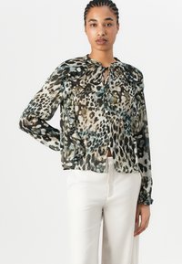 Blůza s leopardím potiskem, vázáním u krku, dlouhými rukávy a volánkovými detaily. Průhledná látka v odstínech černé, béžové a modré. Zapínání na knoflíky.