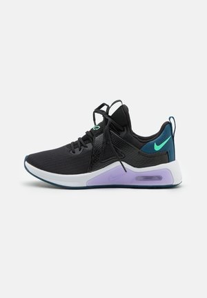 Baskets de sport noires avec logo Nike bleu sarcelle, amorti violet dans la semelle blanche, lacets noirs et languette talonnière bleu sarcelle sur fond gris.