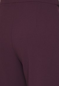 Bordó legíny z hladké, pružné látky. Mají vysoký pas a bezšvový design bez viditelných kapes nebo kovových doplňků.