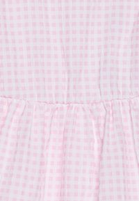 Różowa tkanina w kratkę gingham o miękkiej teksturze, z kwadratami w różnych odcieniach różu. Marszczony szew na dole podkreśla miękkość.