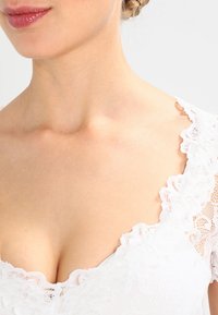 Hvid kjole med en beslag med blonde og ærmer, glat stof med blomster mønstre og en tætsiddende design.