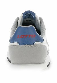 Bela in siva športna obuvala z modrim poudarkom na peti, izdelana iz teksturiranega materiala, podobnega usnju, in z rdečim logotipom "LOTTO" na hrbtnem delu.