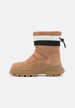 Bottes d'hiver isolées marron et bronzées avec semelle en caoutchouc épaisse et haut de tige color-block noir et blanc avec cordon de serrage réglable.