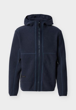 Tmavomodrá flísová bunda s kapucňou, celoprepínacím zipsom vpredu, dvoma bočnými vreckami so zipsom a viditeľnými švami na rukávoch a trupe.