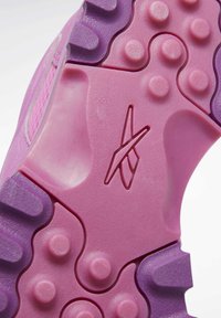 Semelle de sneaker rose et violette avec grip texturé, picots arrondis et logo géométrique embossé au centre.