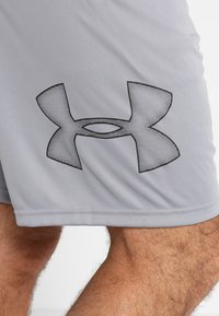 Grijze sportshorts gemaakt van glad materiaal, met een groot zwart Under Armour-logo aan de onderzijde links en een rechte zoom.