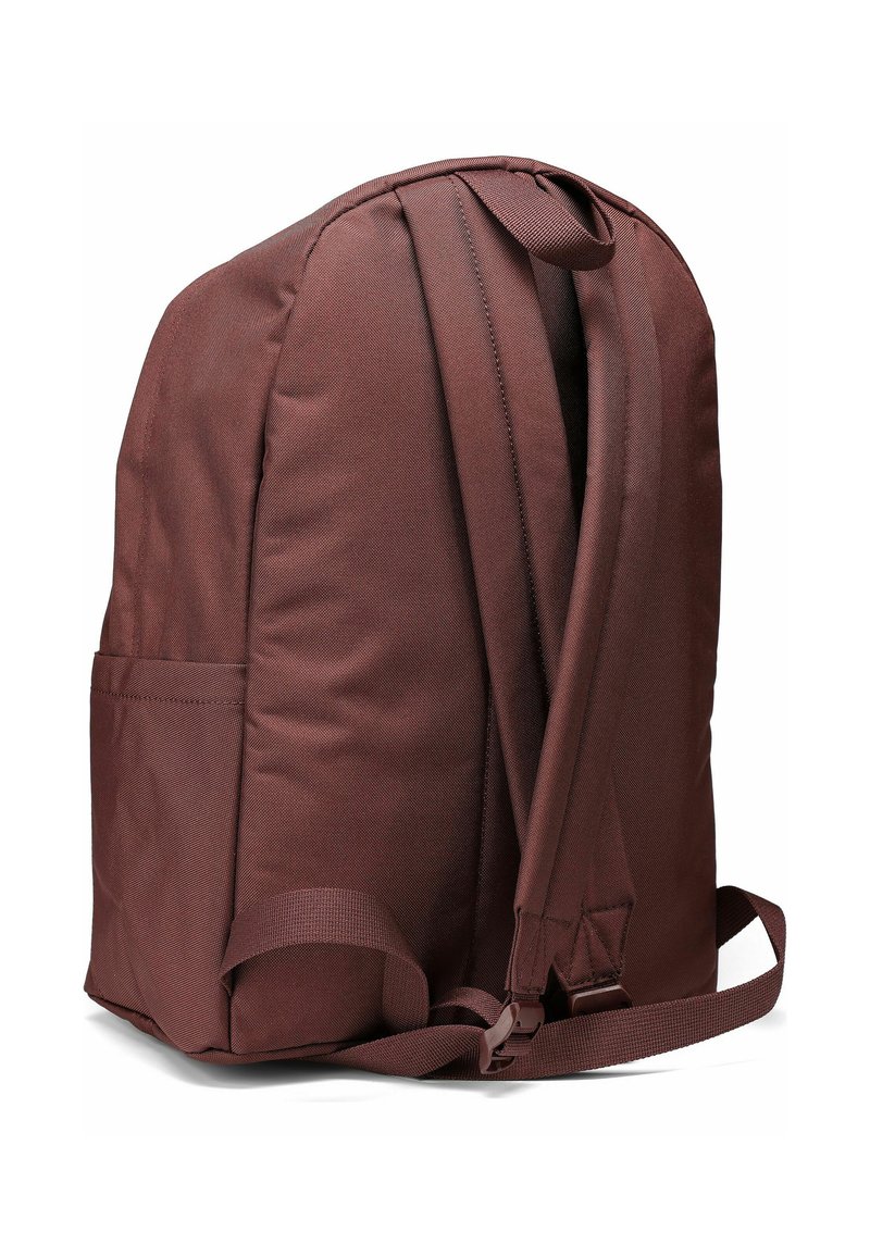 Brown fabric backpack with padded shoulder straps, single side pocket, rounded shape, and minimalistic design.