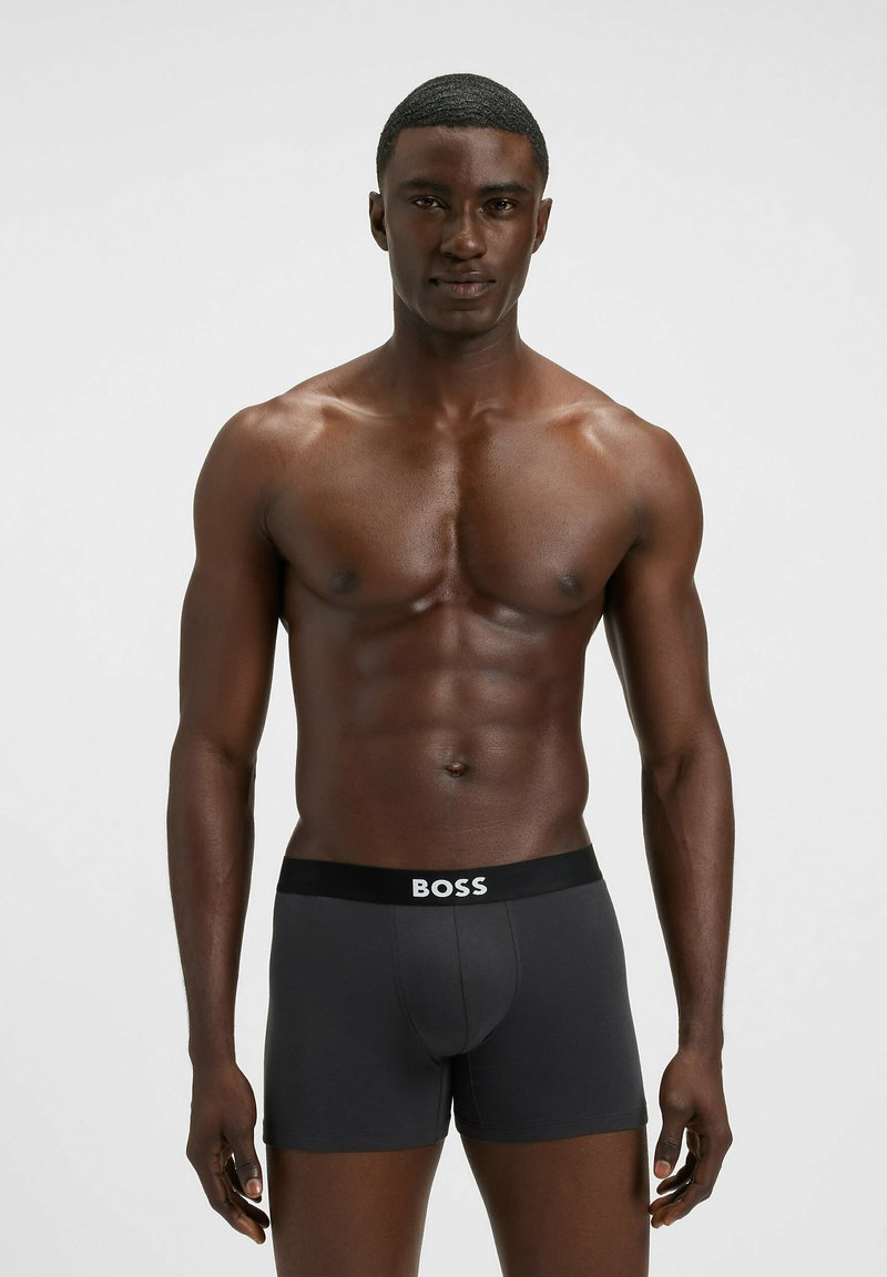 Boxer neri con logo "BOSS" bianco su una fascia larga in vita. Realizzati in cotone elasticizzato, design aderente con texture liscia.