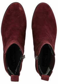 Par de botas de ante burdeos hasta el tobillo con cremalleras laterales y lengüetas de tiro, vistas desde arriba sobre un fondo blanco.