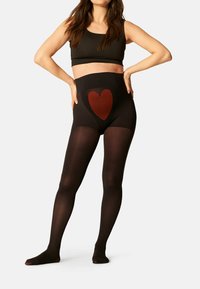 Leggings neri a vita alta con finitura trasparente, caratterizzati da un design centrale a cuore rosso sul davanti e una texture liscia.