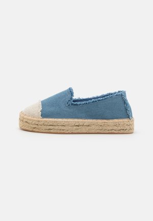 Denim espadrille med en blå overdel, flossede kanter og en lys beige tåhætte. Har en vævet jute sål for tekstur og fleksibilitet.