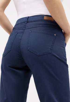 Pantalons ajustés bleu marine en tissu lisse. Comprend deux poches arrière, un patch en cuir au niveau de la taille et un design épuré.