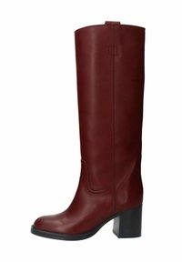 Bottes longues en cuir rouge avec une texture lisse, talon bloc et détail de couture courbée sur la tige. Design simple, sans matériel visible.