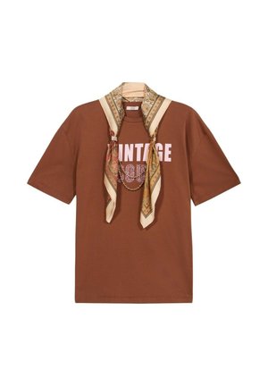 T-shirt marron à manches courtes avec imprime "VINTAGE", stylé avec une écharpe beige à motifs et dorée drapée autour du col.