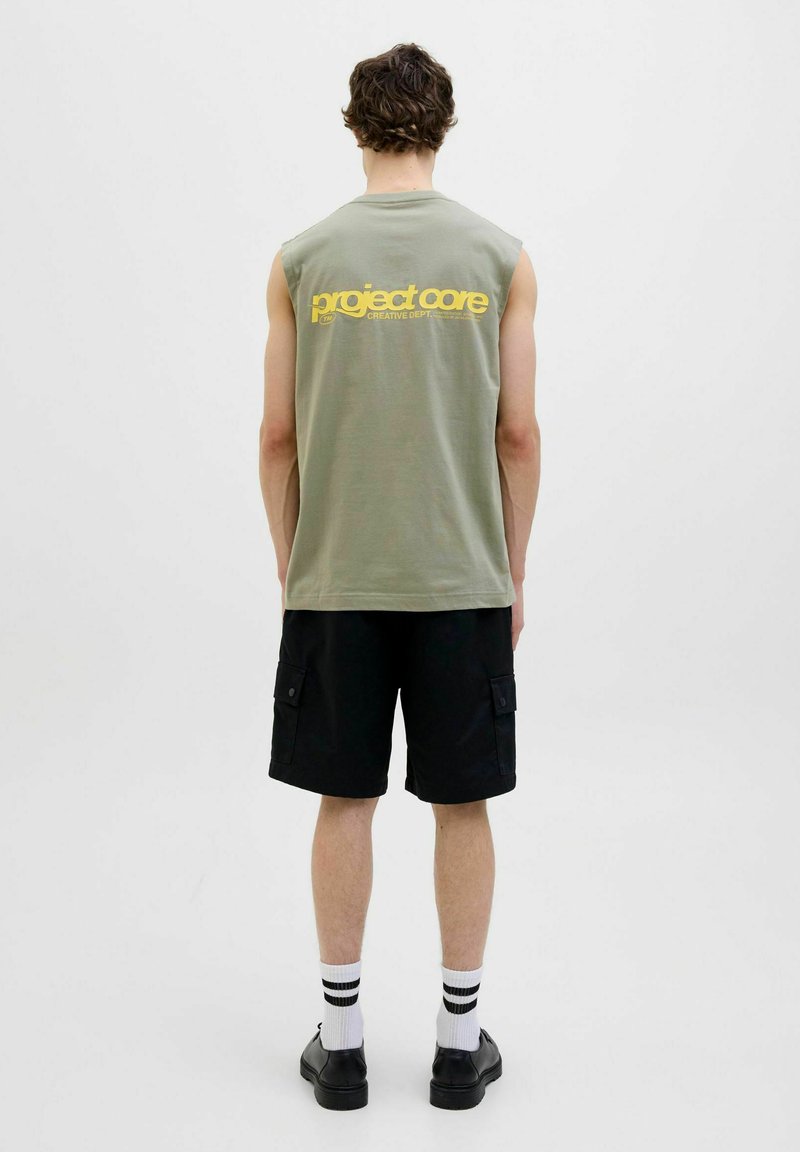 Oliven grøn ærmeløs t-shirt med et gult trykt logo på ryggen, parret med sorte cargoshorts og hvide stribede sokker.