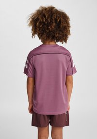 Fioletowy sportowy T-shirt z krótkimi rękawami i teksturowanym materiałem. Posiada poziomą szew na plecach oraz logo na lewym rękawie.