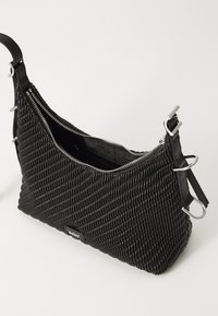Μαύρη πλεκτή τσάντα με καμπύλο σχήμα, ασημένιο κλείσιμο φερμουάρ και διπλές επιλογές λουριών. Υφασμάτινη επιφάνεια με μεταλλικές λεπτομέρειες.