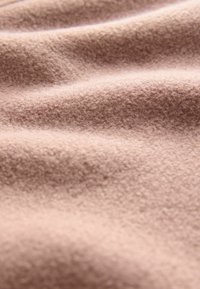 Zacht beige stof met een subtiele textuur, gekenmerkt door zachte plooien en een gladde afwerking, geschikt voor kleding of stoffering.