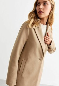 Beige wollen blend jas met een geklikte revers, sluiting met één knop en zijzakken. Gladde textuur en op maat gemaakte vorm voor een getailleerd uiterlijk.