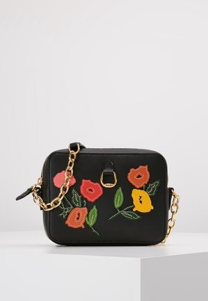 Sac à main rectangulaire noir avec des motifs floraux colorés brodés et une bandoulière chaîne dorée sur une surface blanche.