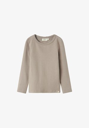 Langärmliges Hemd aus weichem, hellem beige Stoff. Es hat einen runden Ausschnitt und gerippte Abschlüsse, mit einem kleinen Markenetikett am Saum.