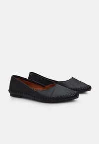 Pantofi negri, plat, din piele netedă, cu vârf ascuțit și detalii cusute pe margini. Interiorul este de culoare maronie și texturat pentru confort.