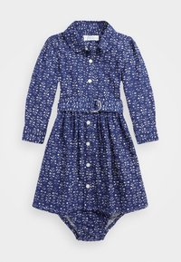 Långärmad klänning i marinblå bomull med vitt blommönster, knappstängning framtill, krage och midjebälte med en cirkulär spänne; elastisk nederkant.