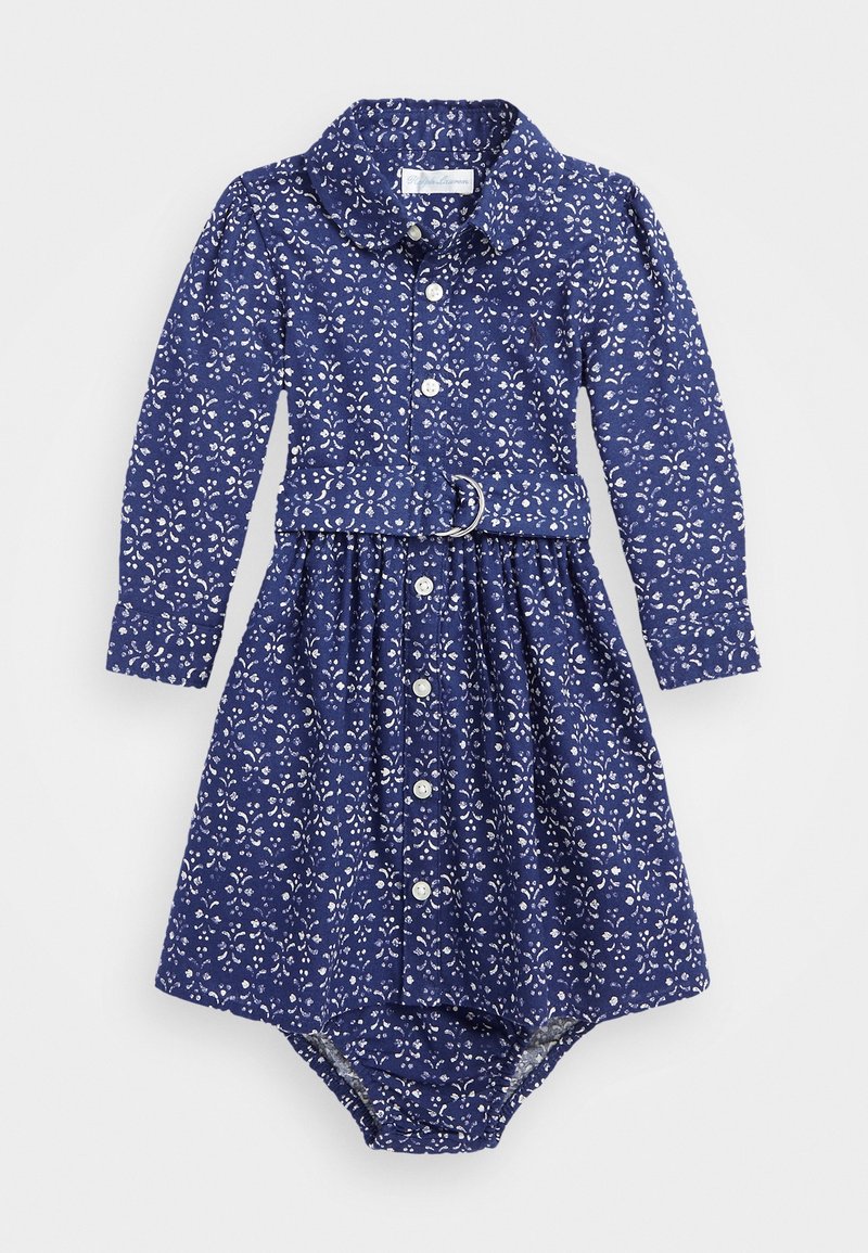 Långärmad klänning i marinblå bomull med vitt blommönster, knappstängning framtill, krage och midjebälte med en cirkulär spänne; elastisk nederkant.