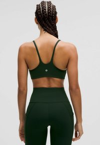 Sostenedor deportivo de un verde oscuro y leggings de cintura alta fabricados en una tela suave y elástica. El sostén cuenta con tirantes finos y un detalle de logo en la parte posterior.