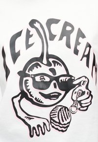 Καρτούν φρούτο χαρακτήρας με γυαλιά ηλίου κρατά ένα μικρό κουταλάκι και μια μπάλα παγωτού, με στυλιζαρισμένο κείμενο από πάνω.