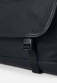 Borsa rettangolare nera con tessuto testurizzato, dotata di chiusura a fibbia magnetica e bordi lisci lungo il perimetro.