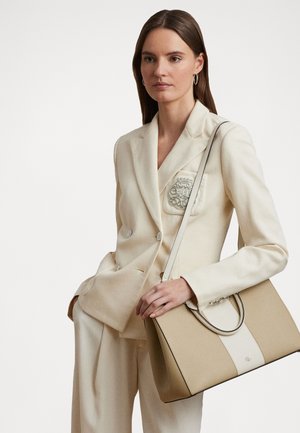 Krema blazer z lepo krojem in vezenim detajlom na žepu, v kombinaciji z bež strukturirano torbico z zgornjim ročajem in kontrastnimi črtami.