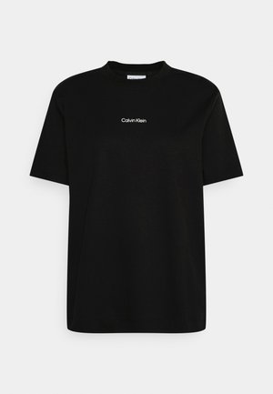 Camiseta de algodón negra con cuello redondo y mangas cortas, que presenta un pequeño logo blanco de "Calvin Klein" en el frente.