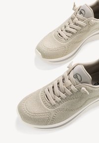 Bēšas auduma kedas ar teksturētu apdari, apaļu purngalu, bēšām šņorēm un baltu zoli ar nelielu līkumu. Smalkas šuvju detaļas.